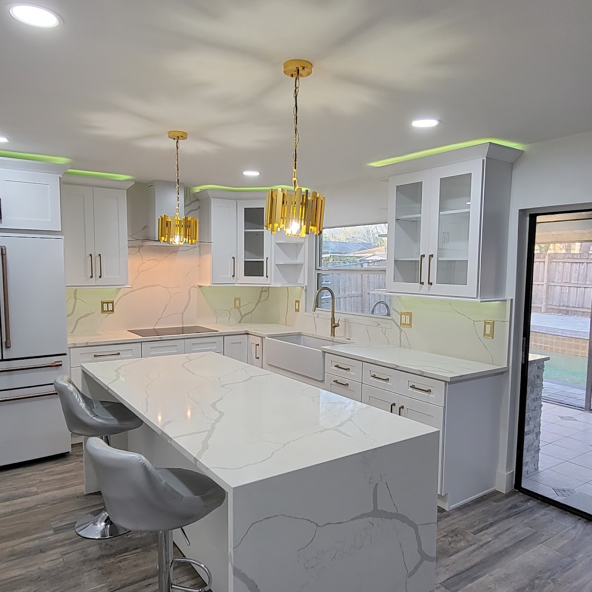 White kitchen cabinets, a waterfall-style island and gold pendant lights