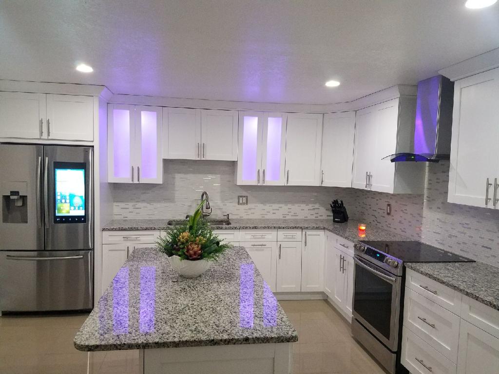 White kitchen cabinetry around a speckled countertop island