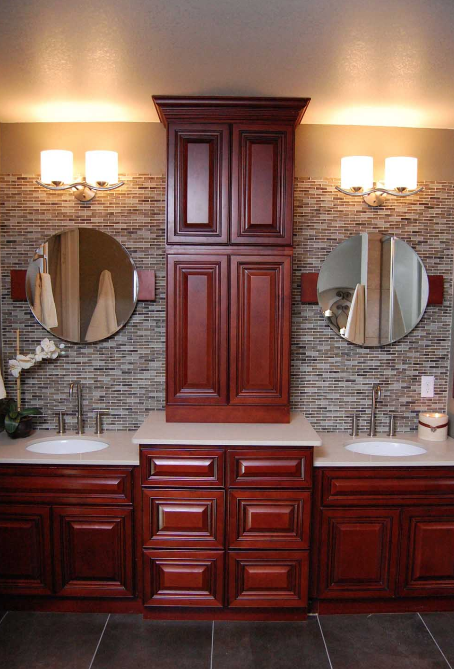 Wood double vanity with a tall center cabinet and round mirrors